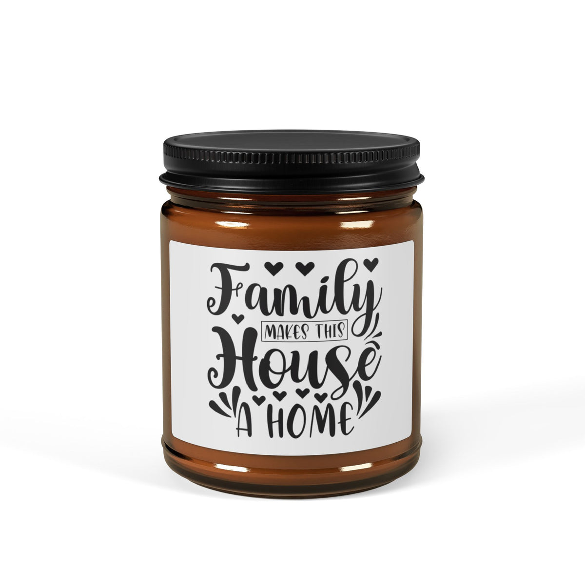An amber glass jar candle with a black metal screw-on lid and a white label that reads 'Family Makes This House A Home' in black script and block lettering, shown on a clean white background.