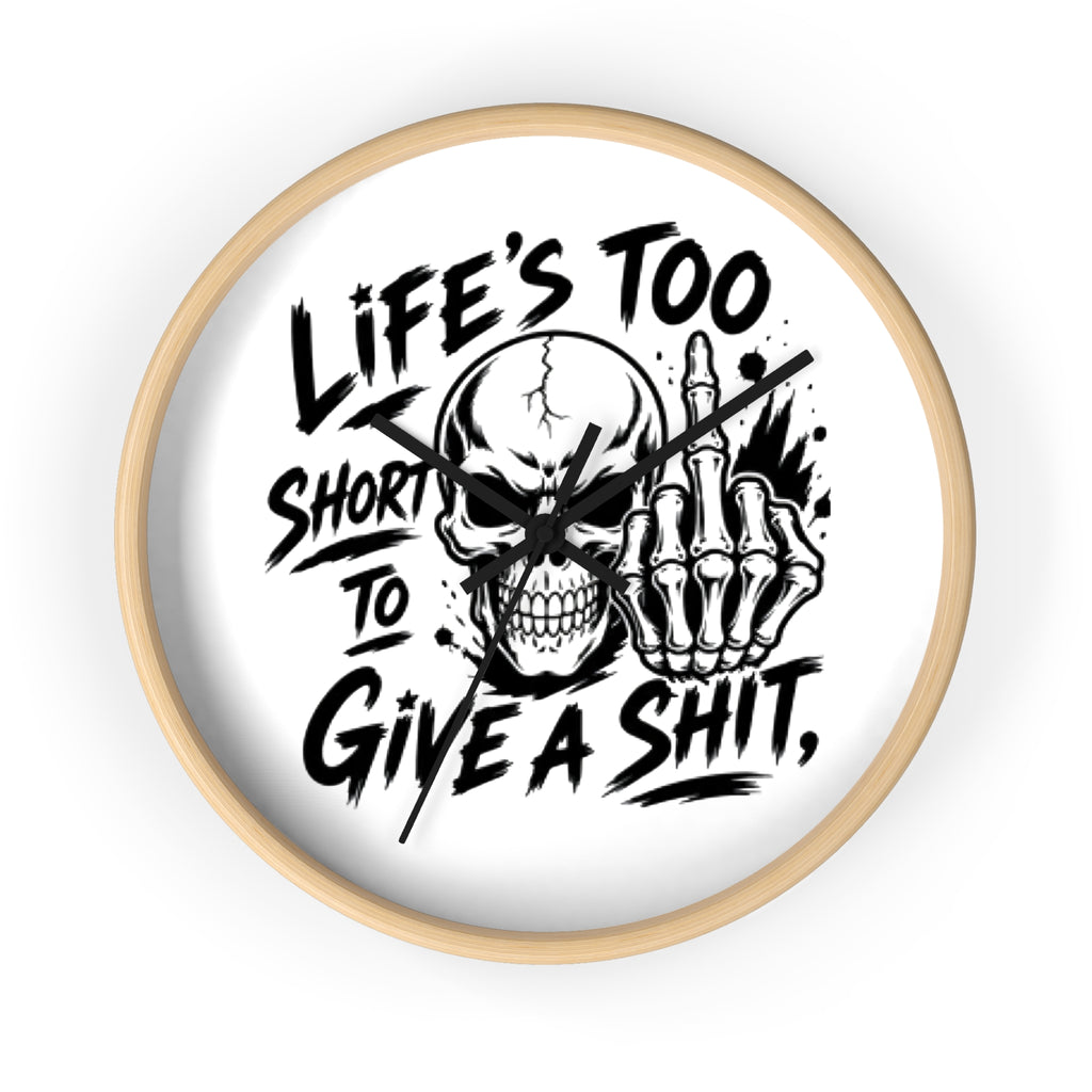 A round wall clock with a light natural wood frame and a white face, featuring a bold black graphic of a skull and skeletal hand making a middle finger gesture, with the text 'LIFE'S TOO SHORT TO GIVE A SHIT,' on a clean white background.