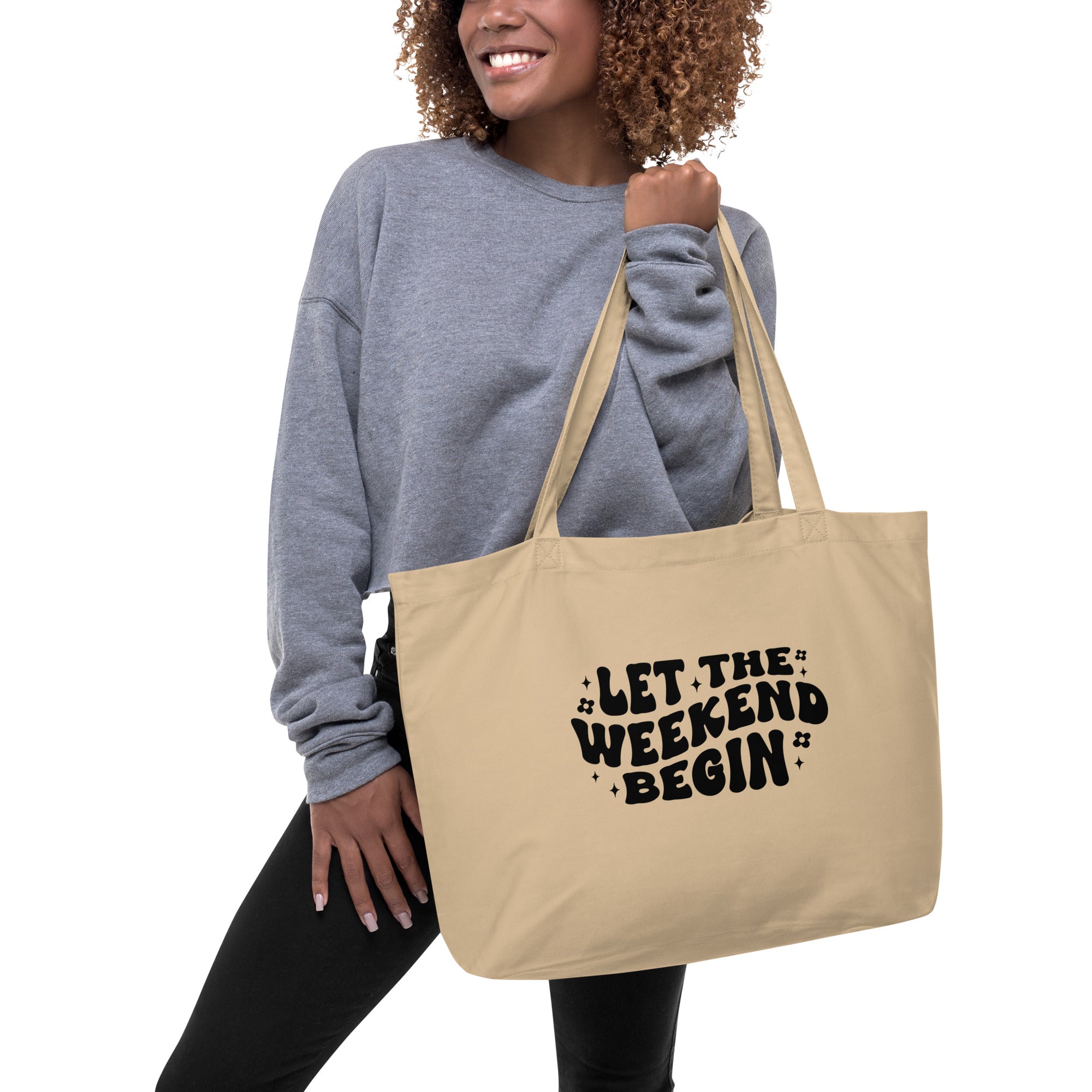 Woman holding a beige tote bag with 'Let the Weekend Begin' text.