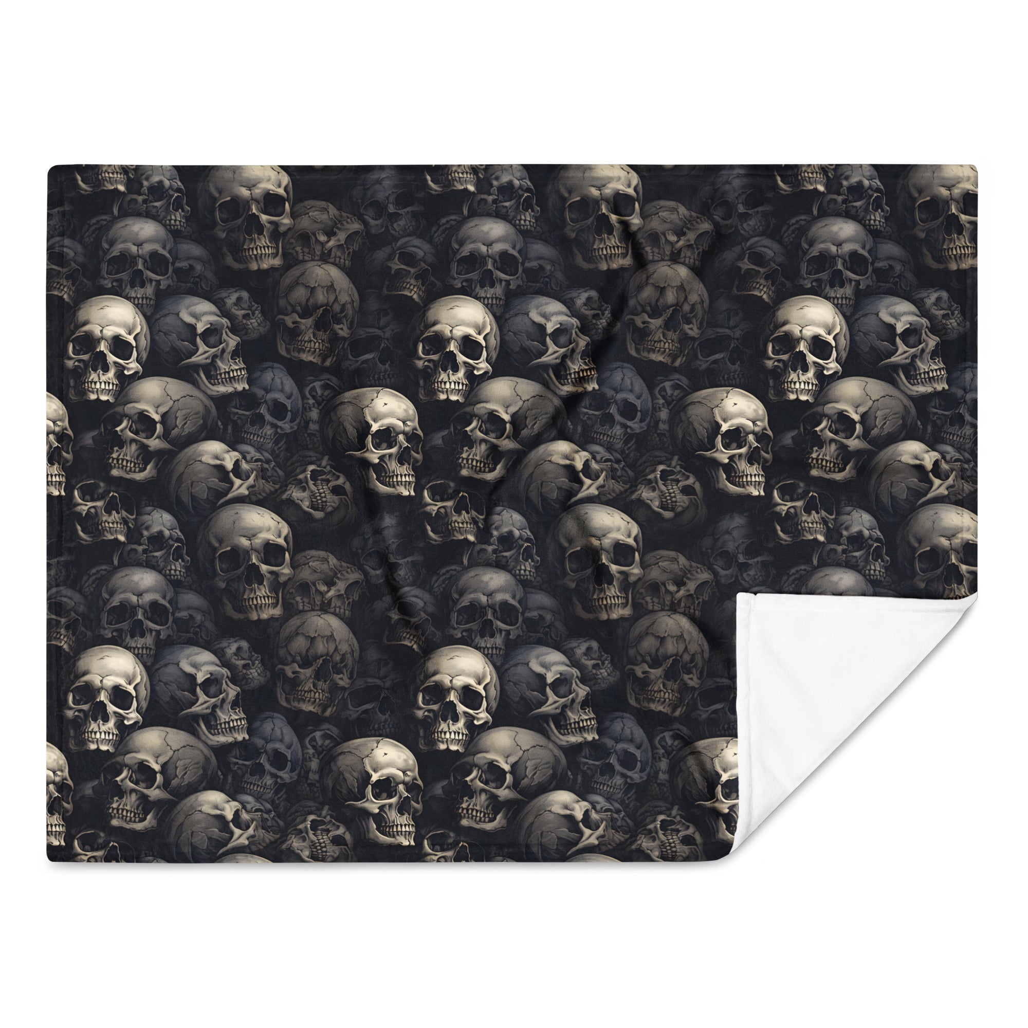 A square throw blanket featuring an all-over repeating skull print in dark gray and black tones, with a folded corner revealing a white reverse side, shown on a plain white background.