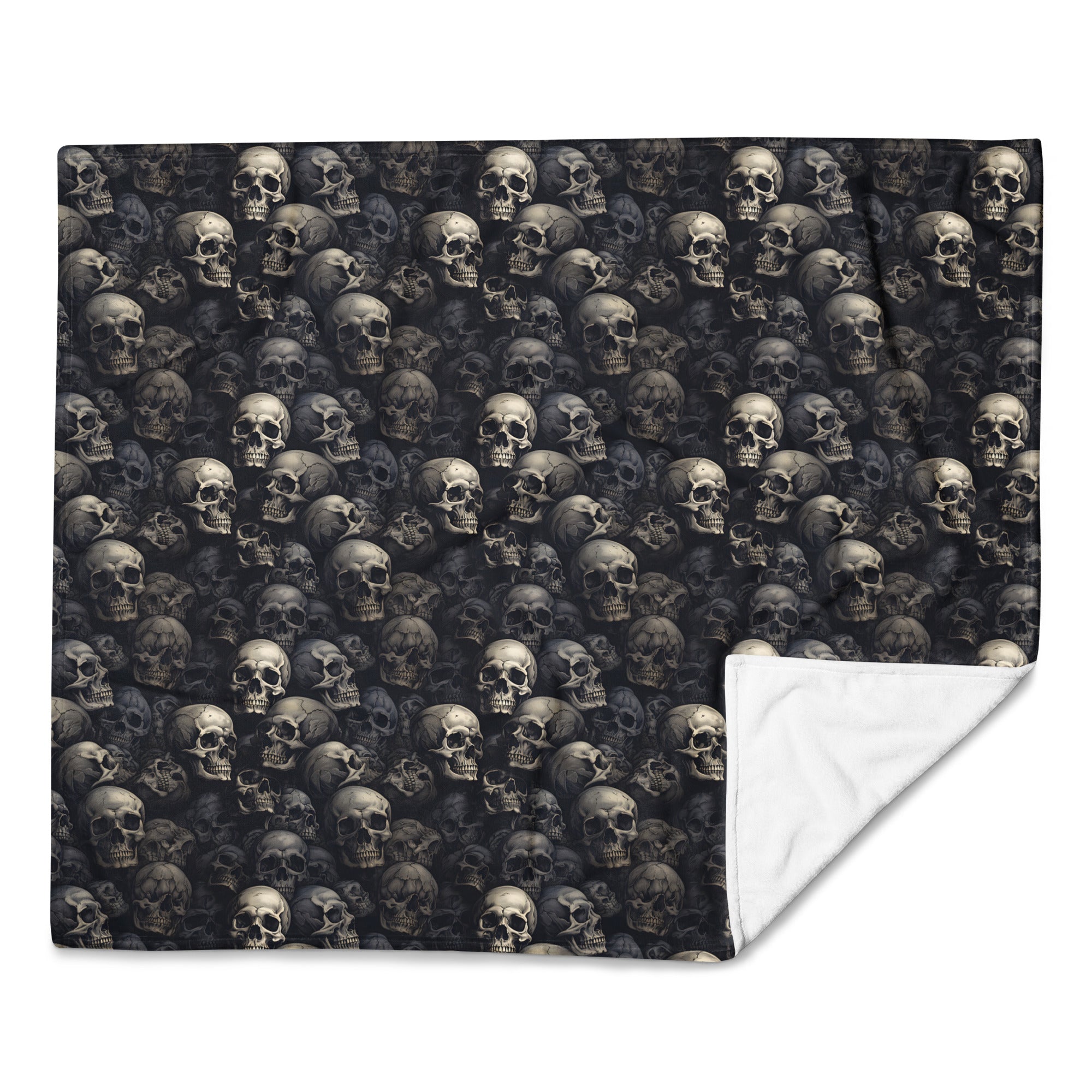 A square throw blanket featuring an all-over repeating skull print on a dark background, with the lower right corner folded over to show a white sherpa-style reverse side, set against a plain white background.