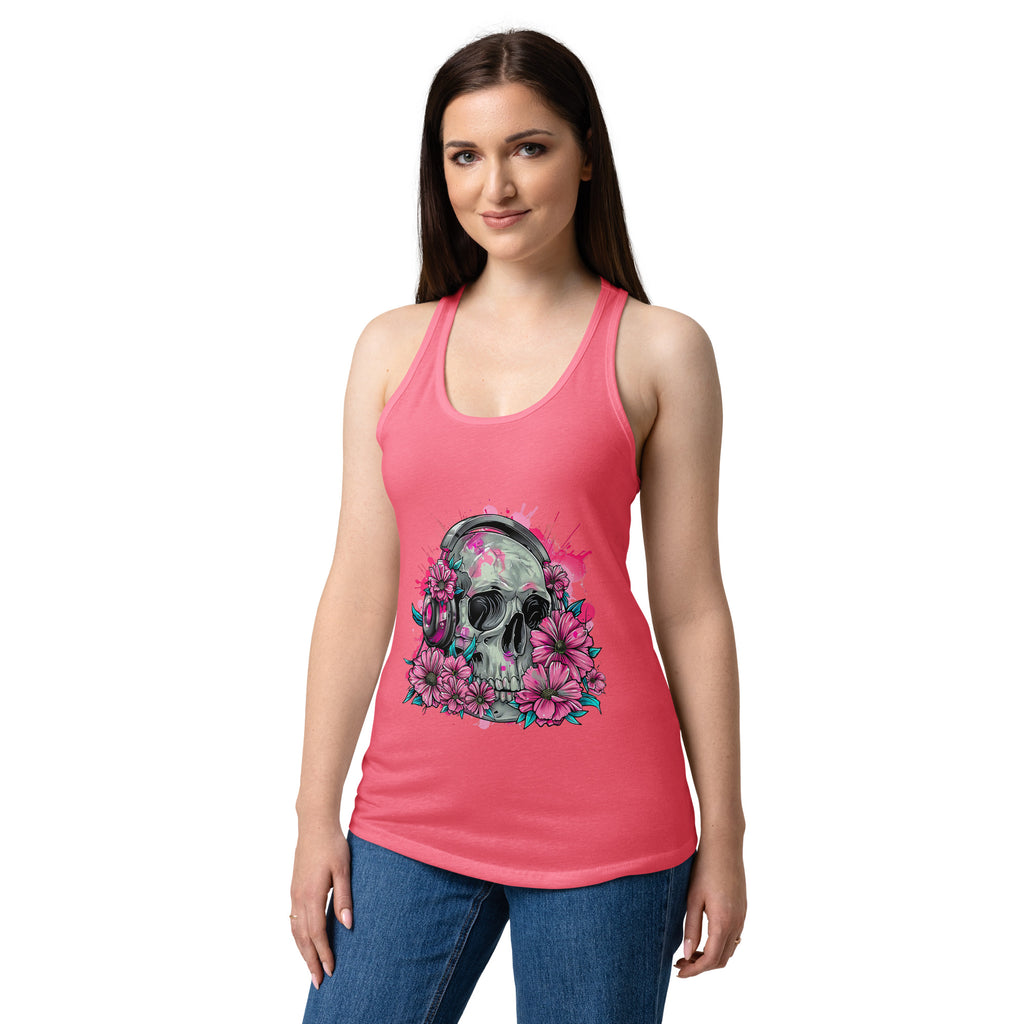 A woman modeling a pink racerback tank top with a graphic of a skull surrounded by pink flowers and headphones, paired with blue jeans against a plain white background.